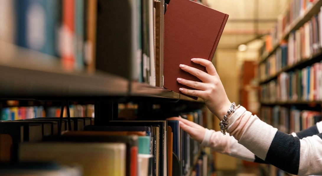 Librarian hands pulling books from a shelf.