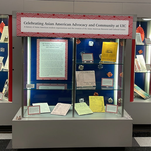 Glass exhibit cases with shelves of archival materials including documents and text labels describing the materials.