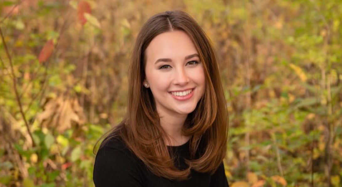 Hannah smiling in front of a green, leafy background