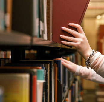 Close-up of someone removing a book from a shelf in the library
                  