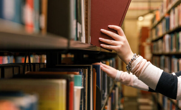 Close-up of someone removing a book from a shelf in the library