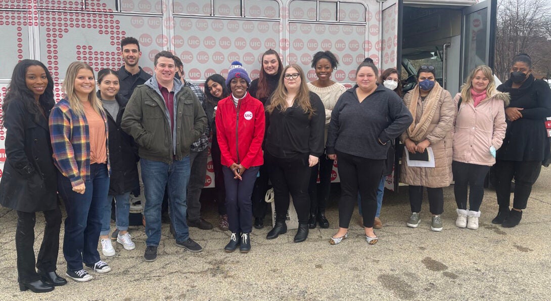 Students and Dean Ballard-Thrower standing in front of a UIC branded bus.