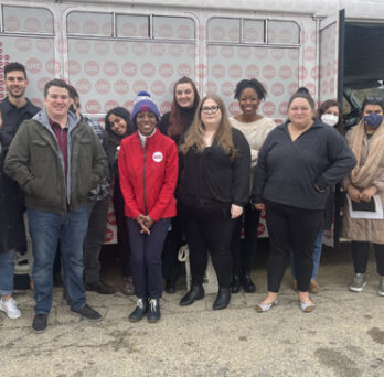 Students and Dean Ballard-Thrower standing in front of a UIC branded bus. 