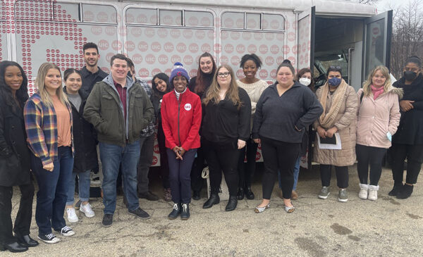 Students and Dean Ballard-Thrower standing in front of a UIC branded bus.