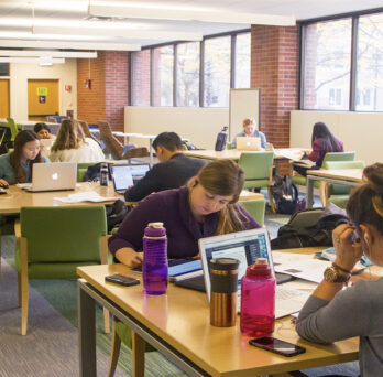 Library users sitting at tables while studying and working on laptop computers in the Library of the Health Sciences-Chicago.
                  