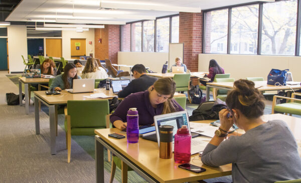 Library users sitting at tables while studying and working on laptop computers in the Library of the Health Sciences-Chicago.