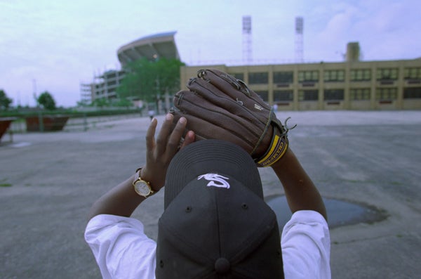 Pierre Williams, a little league player in a Sox cap, practices catching a pop-up. Then Comiskey Park is seen in the background.