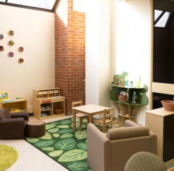 Brightly lit room with toys and comfortable furniture for children and parents.
                  